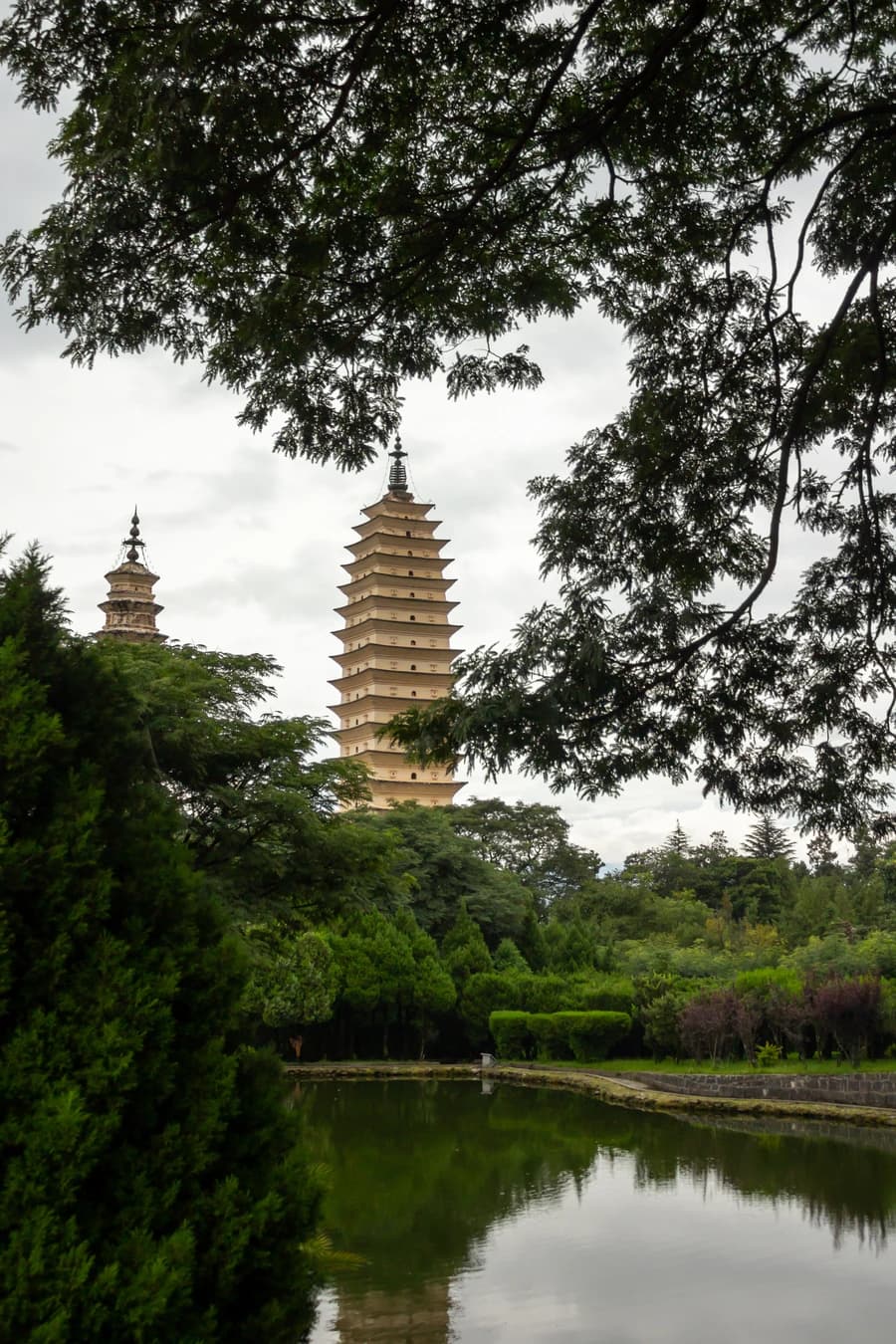 Tres Pagodas enmarcadas por árboles con Cangshan detrás