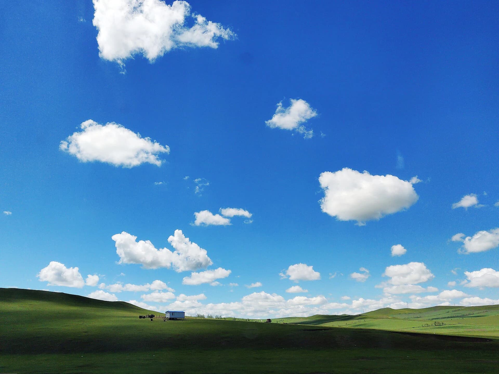 Rolling green grassland under a wide blue sky in Hulunbuir