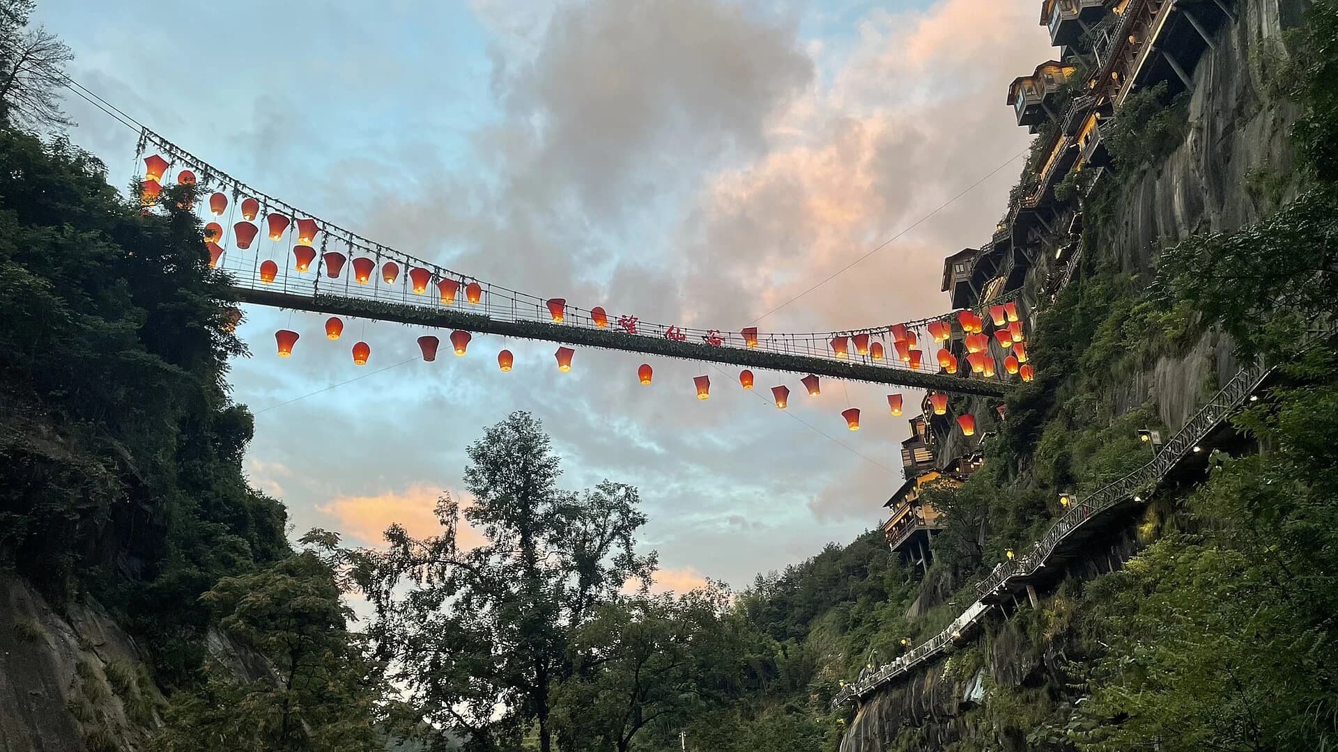 Lantern-lit walkway and cliffside buildings at Wangxian Valley