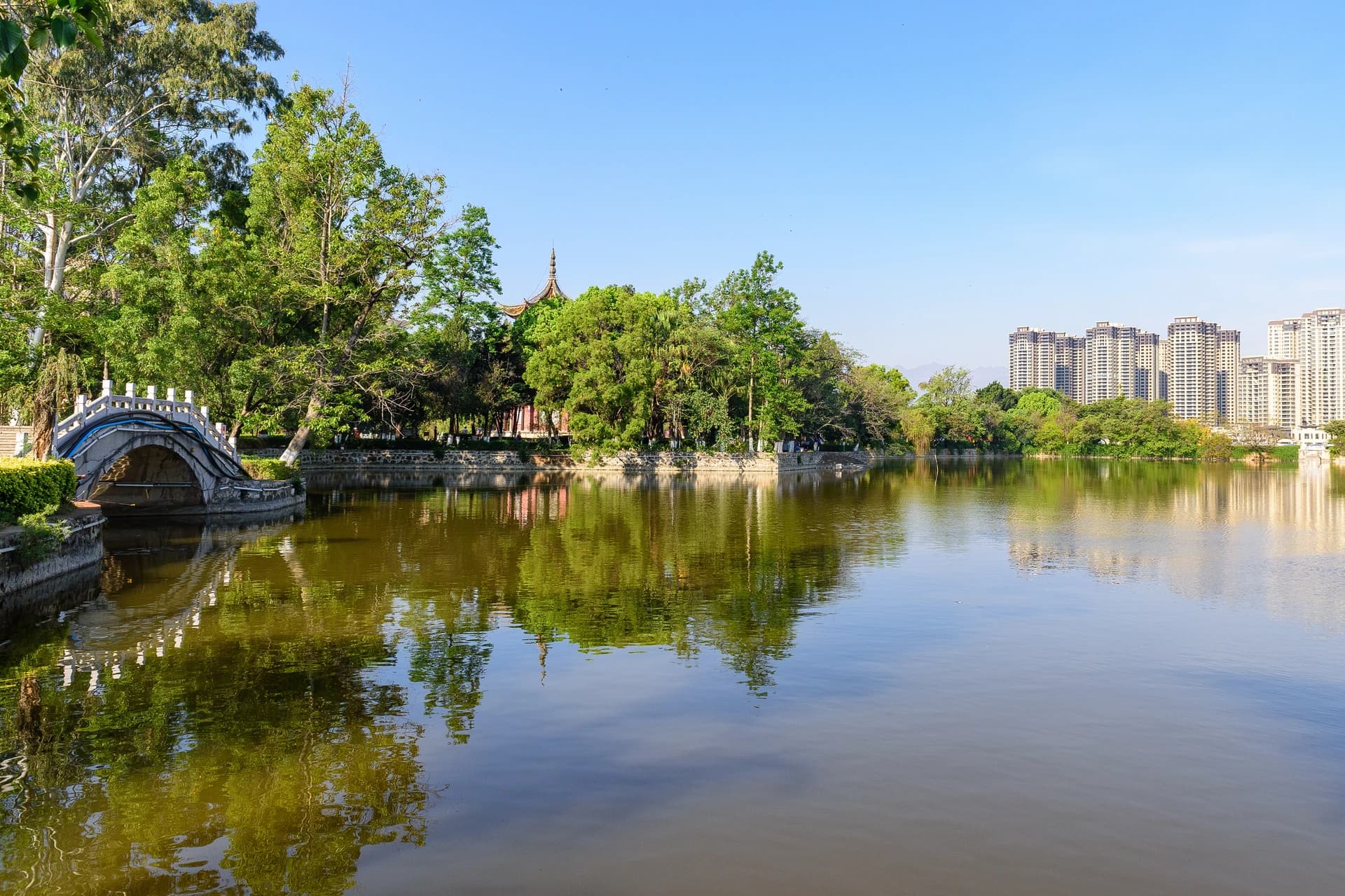 Árboles, puente arqueado y agua en el parque Nanhu de Mengzi