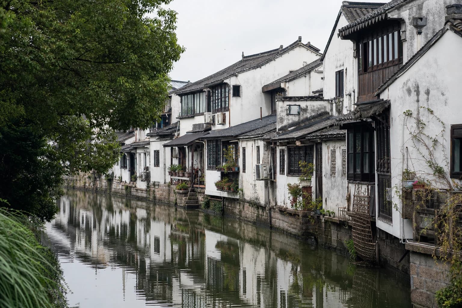 Casas blancas erosionadas junto al agua reflejadas en un canal estrecho