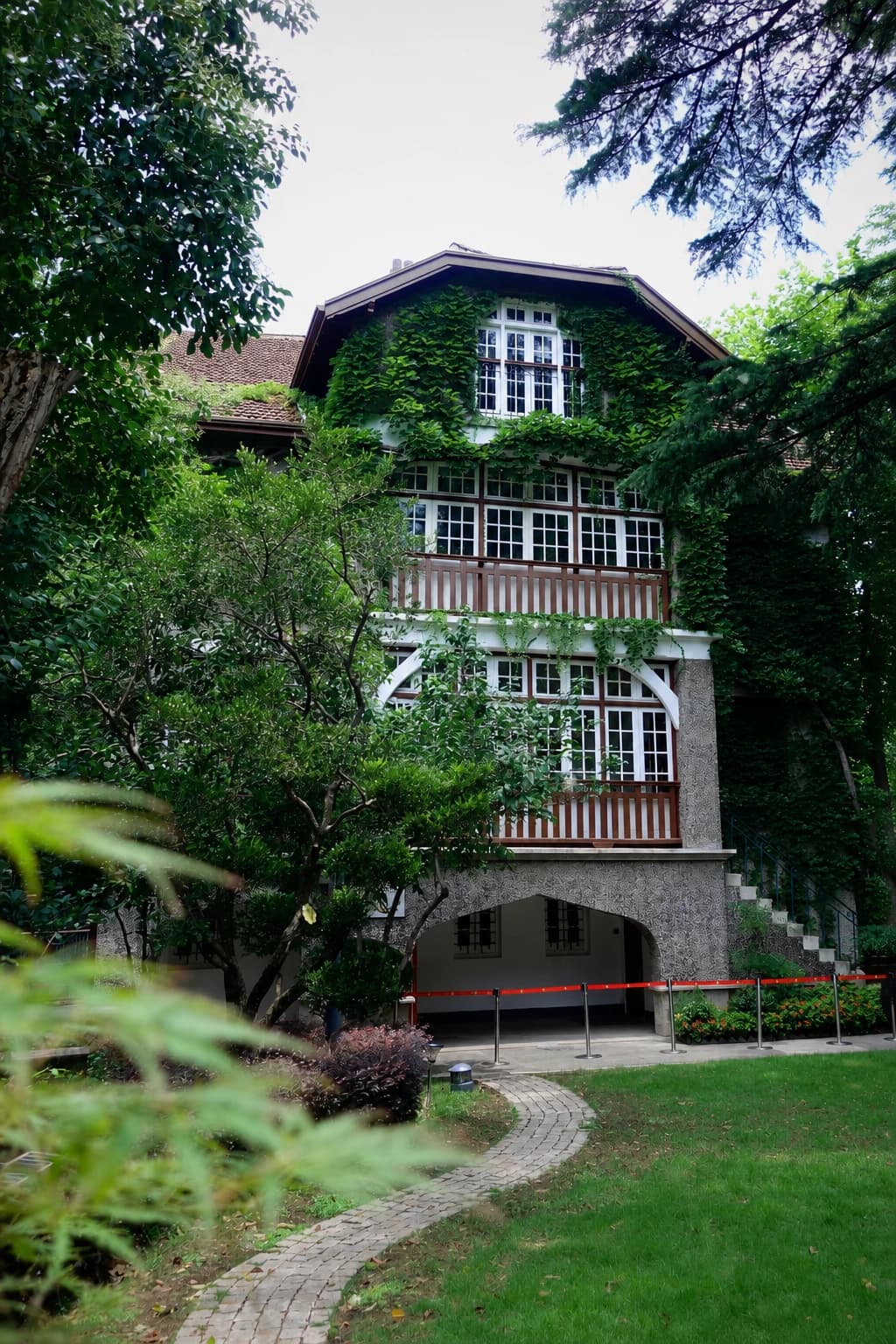 Una histórica casa con jardín enmarcada por hiedra y árboles maduros en Sinan Mansions