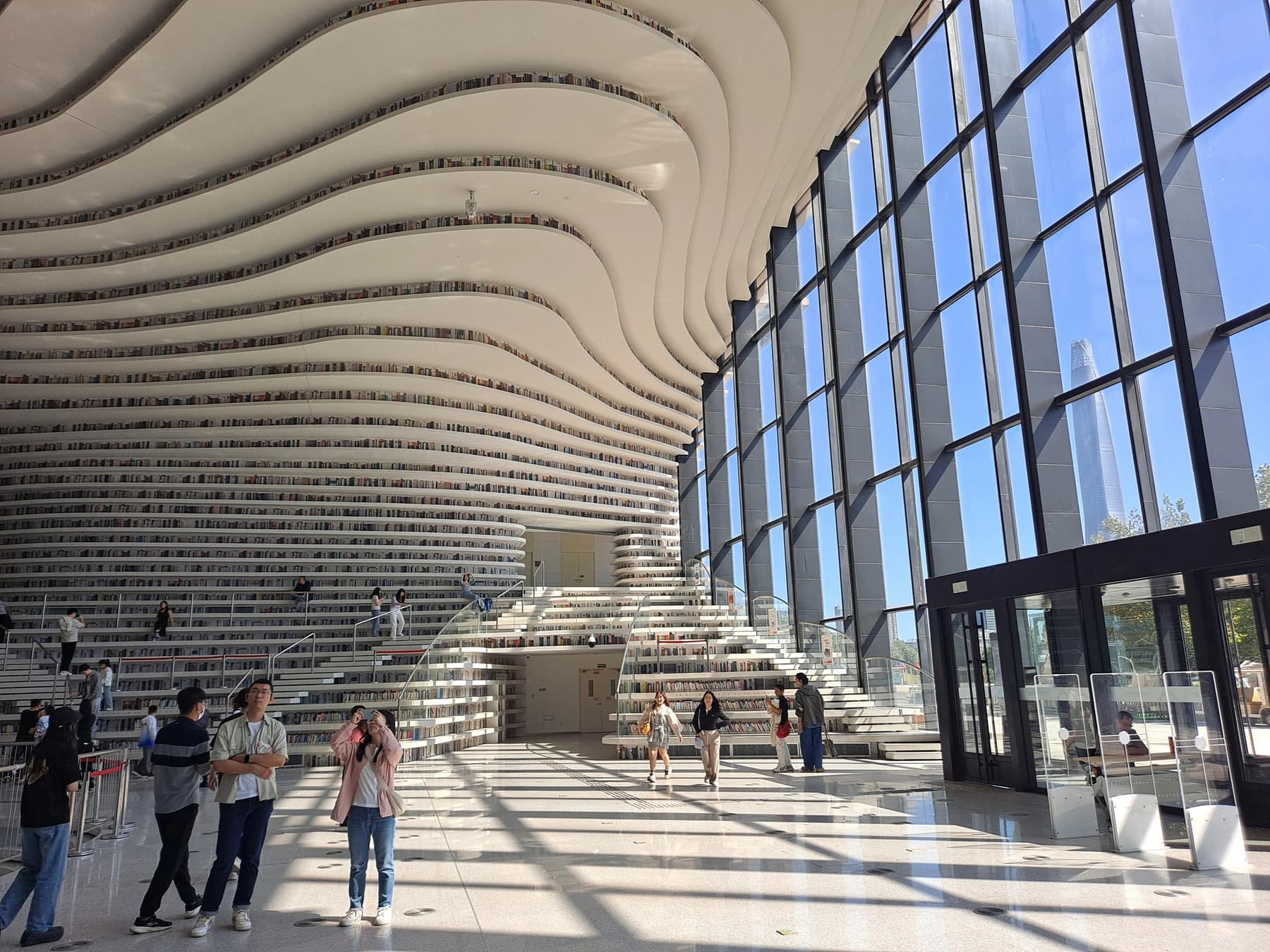 Terrazas curvas y estanterías blancas dentro de la Biblioteca Binhai