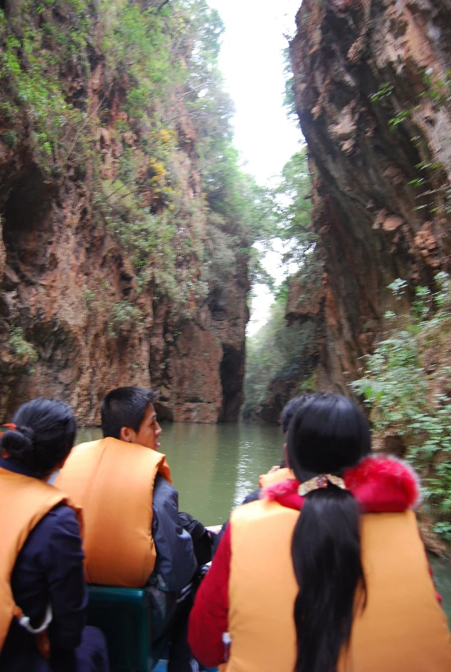 Visitantes en una pequeña embarcación por el estrecho desfiladero fluvial de Jiuxiang