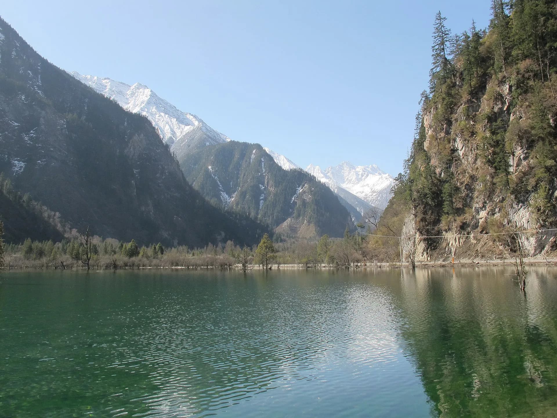 Longwang Lake framed by forest and mountain slopes in Bipenggou
