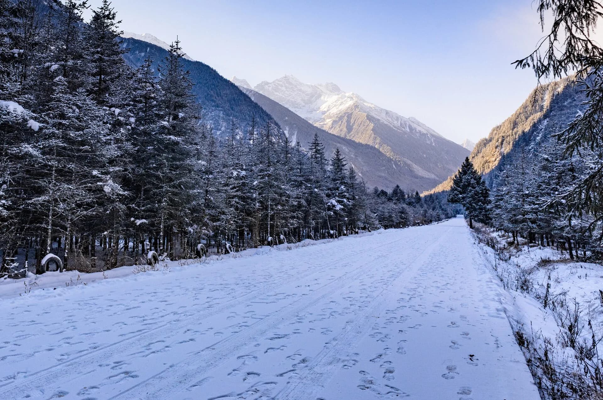 Snow-covered road running through winter forest in Bipenggou