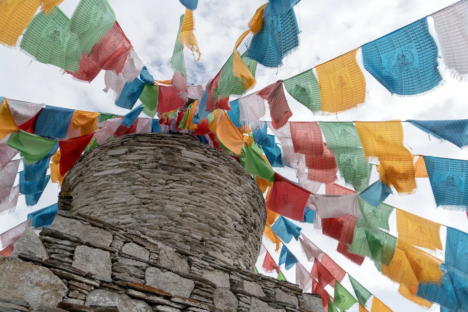 A white stupa and prayer flags in the Mount Siguniang mountain landscape