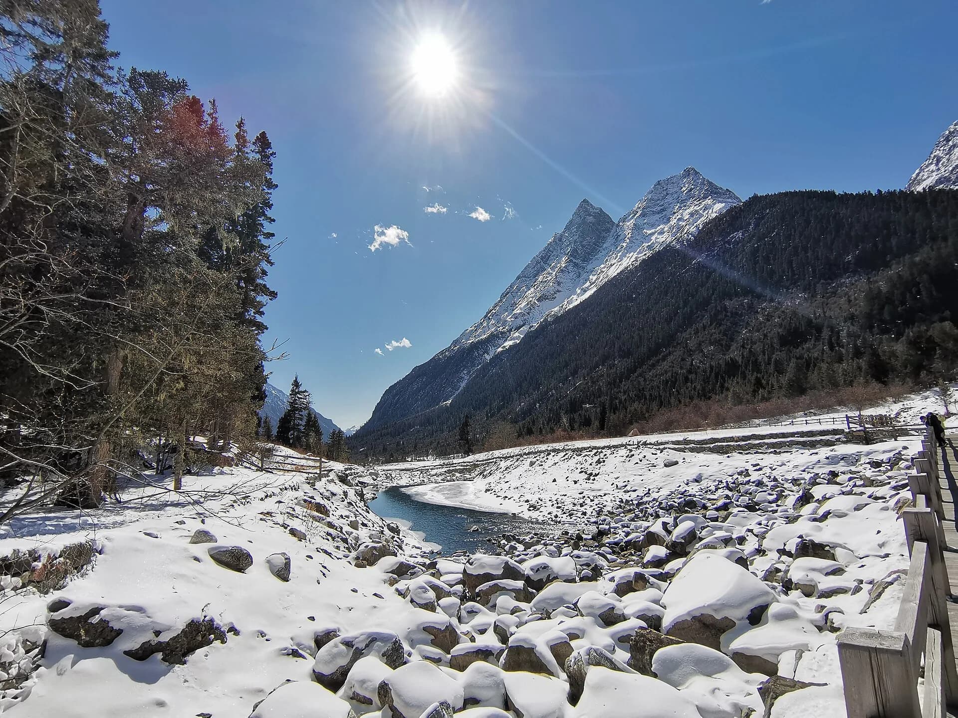 Snow-covered boardwalk and mountain valley scenery in Shuangqiao Valley