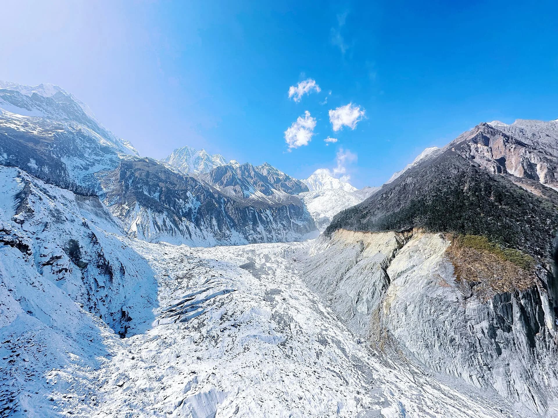 Glacier ice and high peaks rising above the forested Hailuogou valley