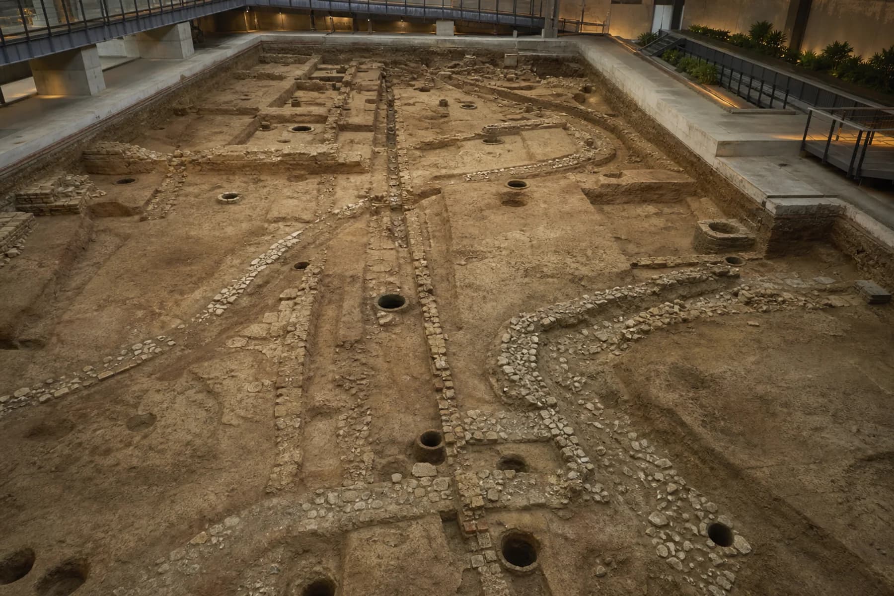 Visualización editorial elevada de canales curvos de piedra, pozos y restos superpuestos en el yacimiento de Nanyue Palace