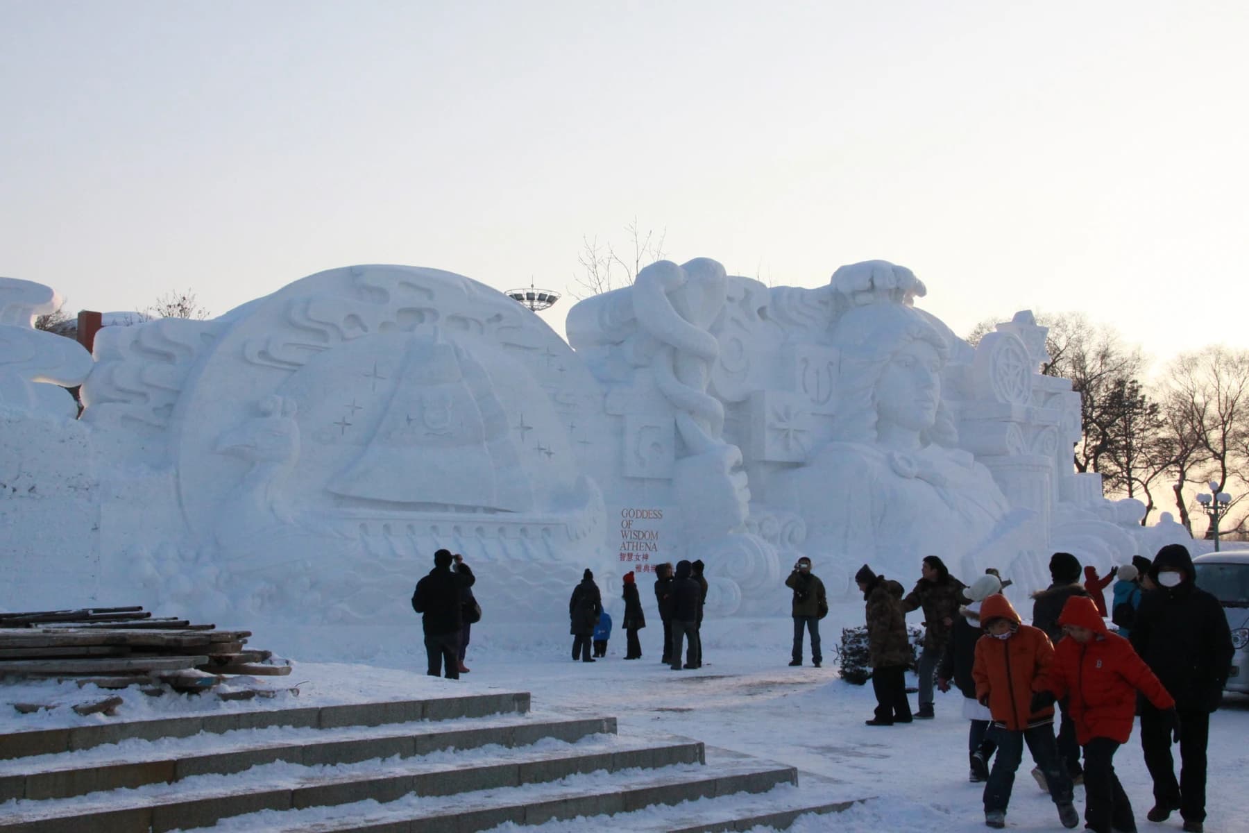Visitantes que muestran la escala de una gran escultura de nieve de la Isla del Sol.