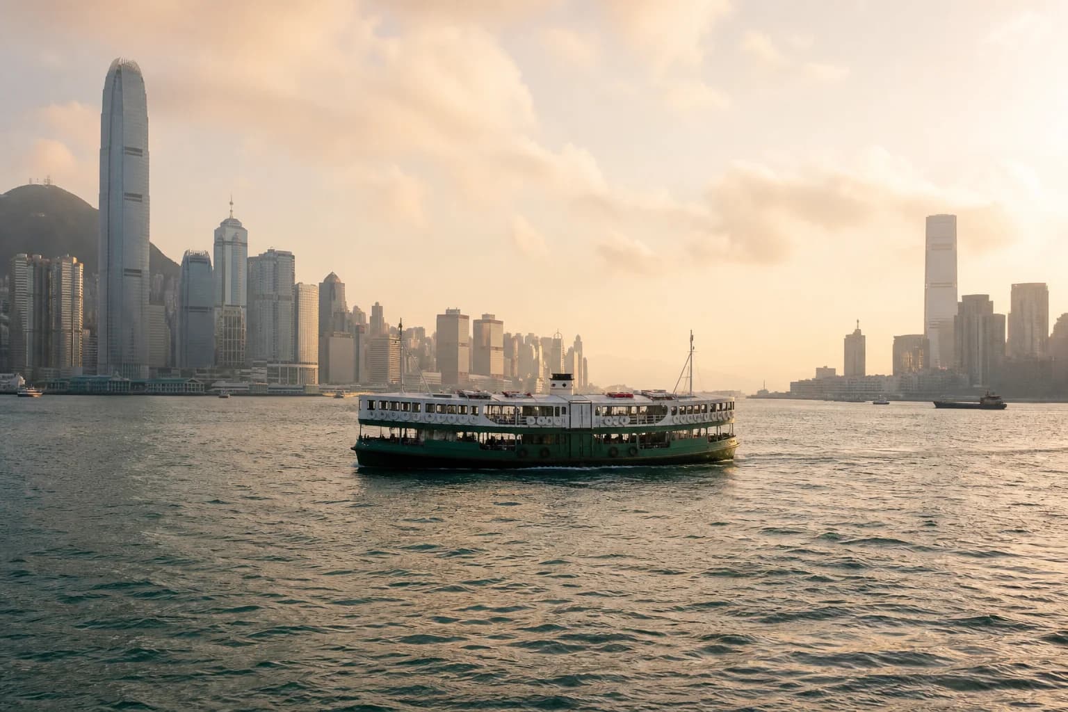 Imagen de un clásico ferry de pasajeros verde y blanco cruzando Victoria Harbour durante la hora dorada