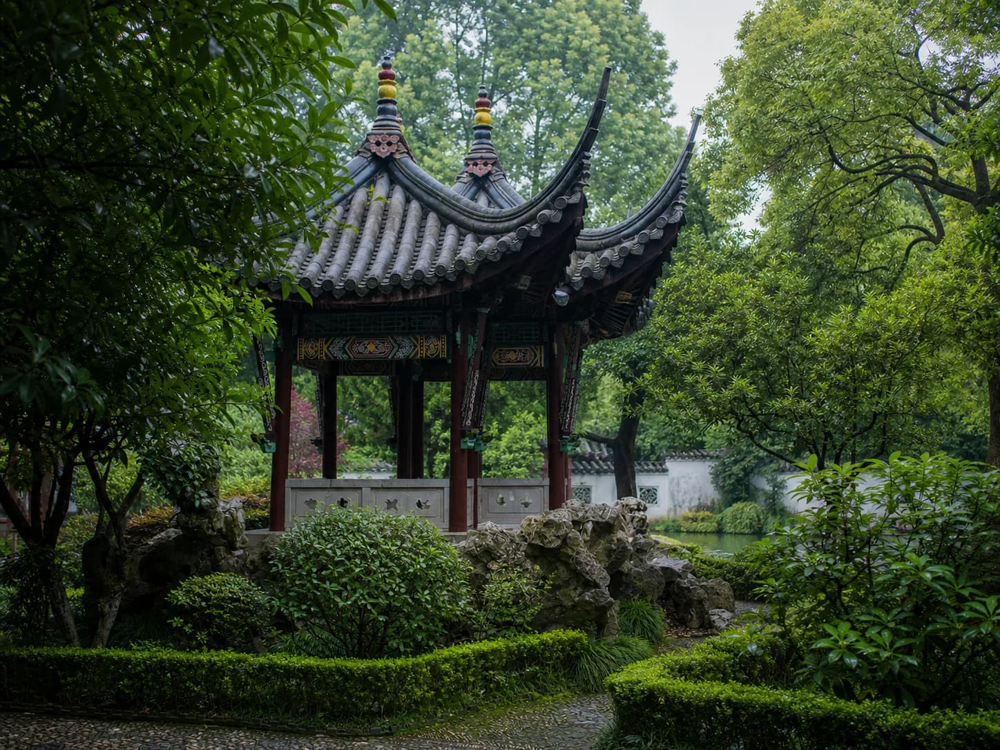 Vista de un pabellón, rocalla y vegetación en el Jardín Xu