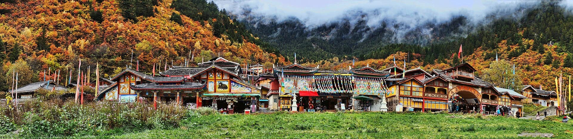 Shuzheng village beneath autumn forest and misty mountains in Jiuzhaigou