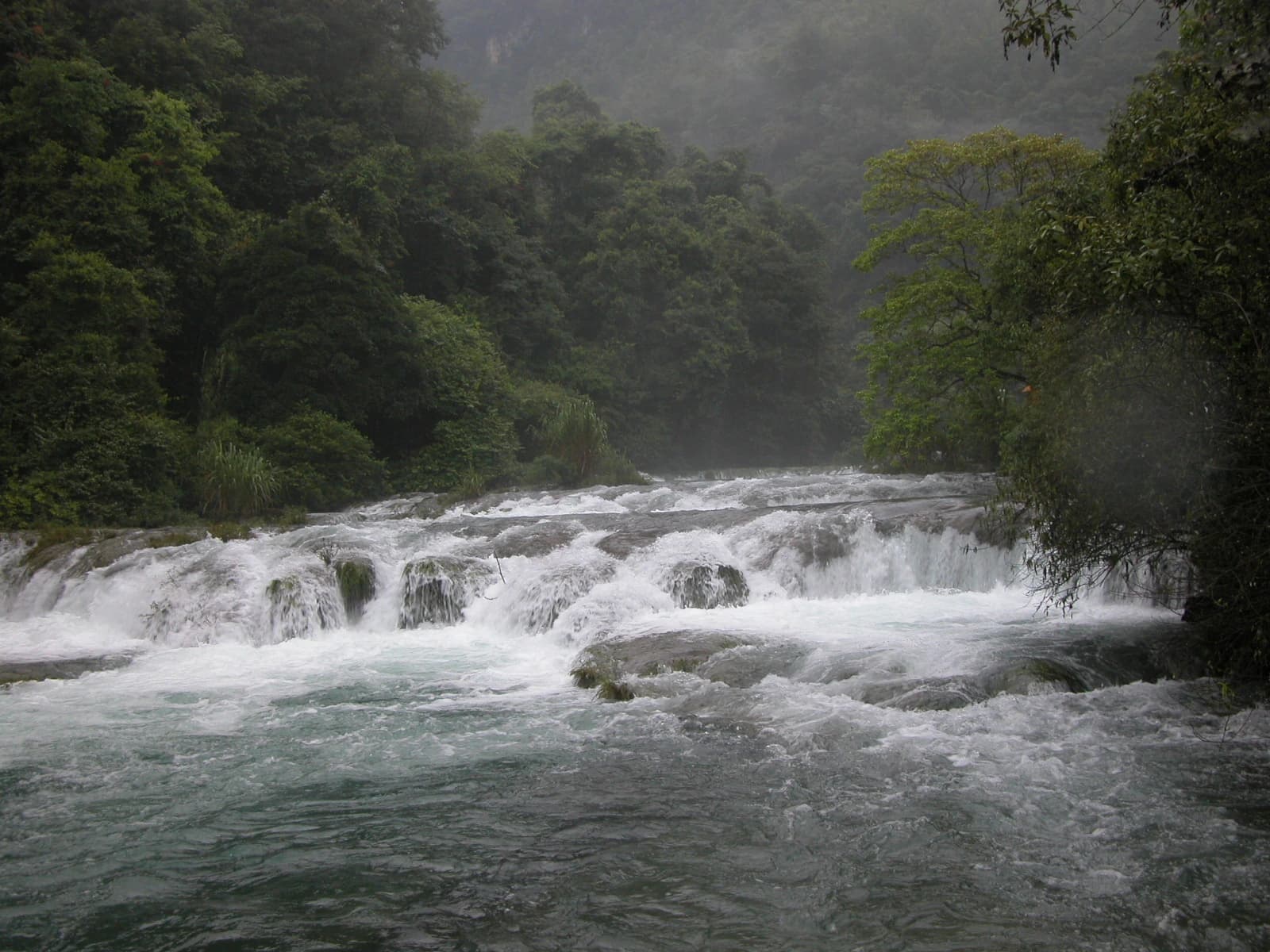 Una amplia cascada atraviesa el bosque junto al sendero principal de Xiaoqikong