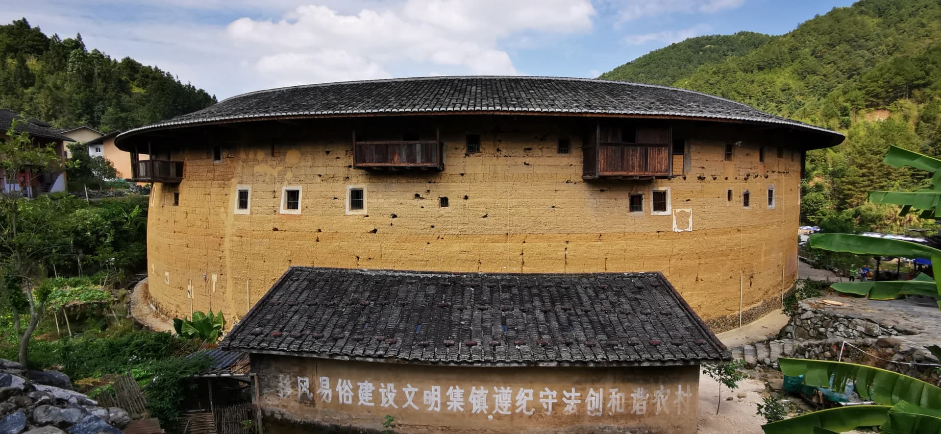 Muro de tierra, tejados y montaña en Chuxi