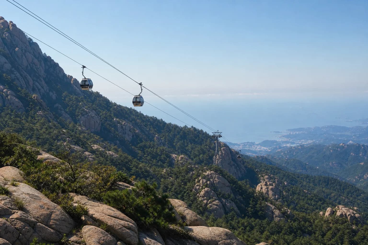 Cabinas del teleférico sobre laderas de granito y pinos en Mount Lao