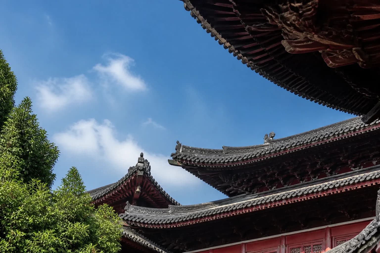 Aleros del templo oscuros en capas y vigas rojas contra un cielo azul