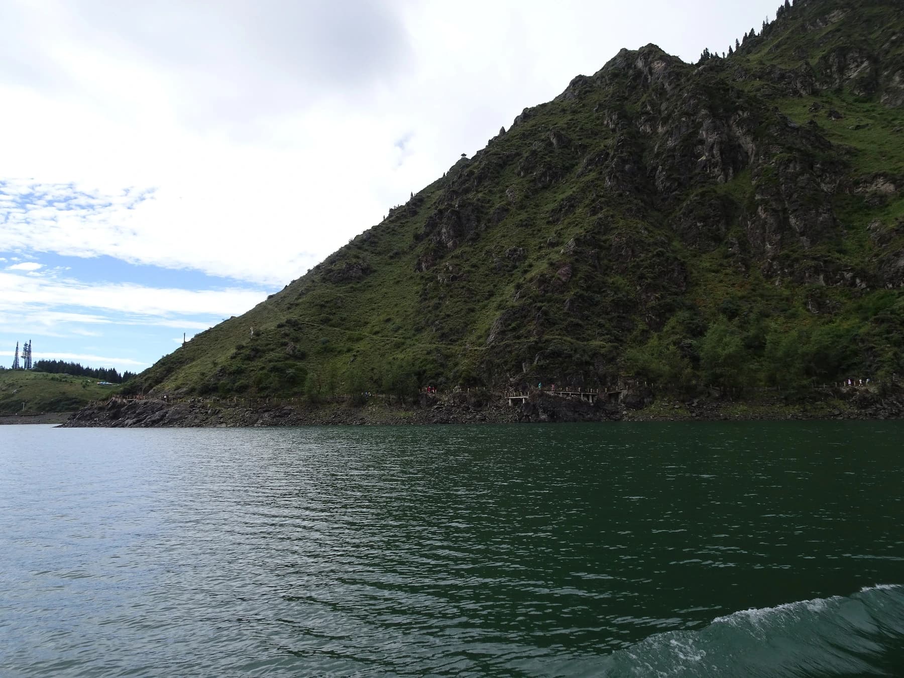 Barco en el lago Heavenly bajo las paredes de la montaña Tianshan