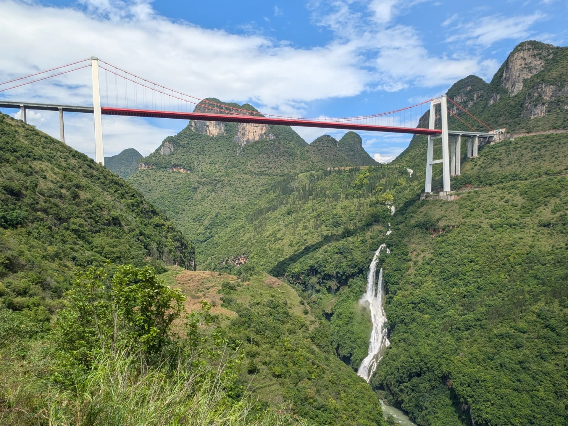 A high bridge and waterfall reveal the scale of the Maling River gorge