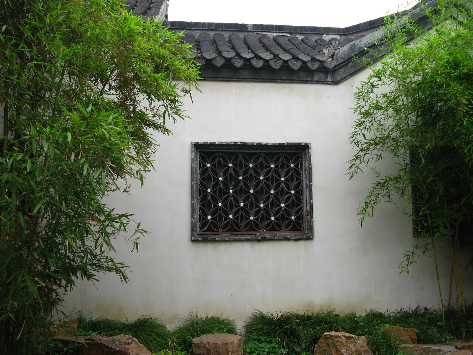 Bamboo framed by a white wall and lattice window in Ge Garden