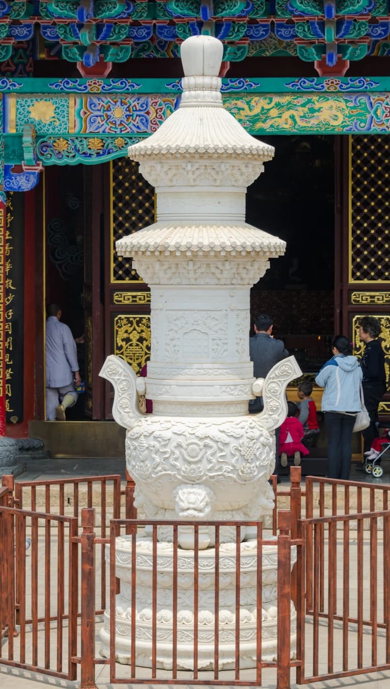 Estructura blanca tallada para el incienso ante un salón del templo Yuantong