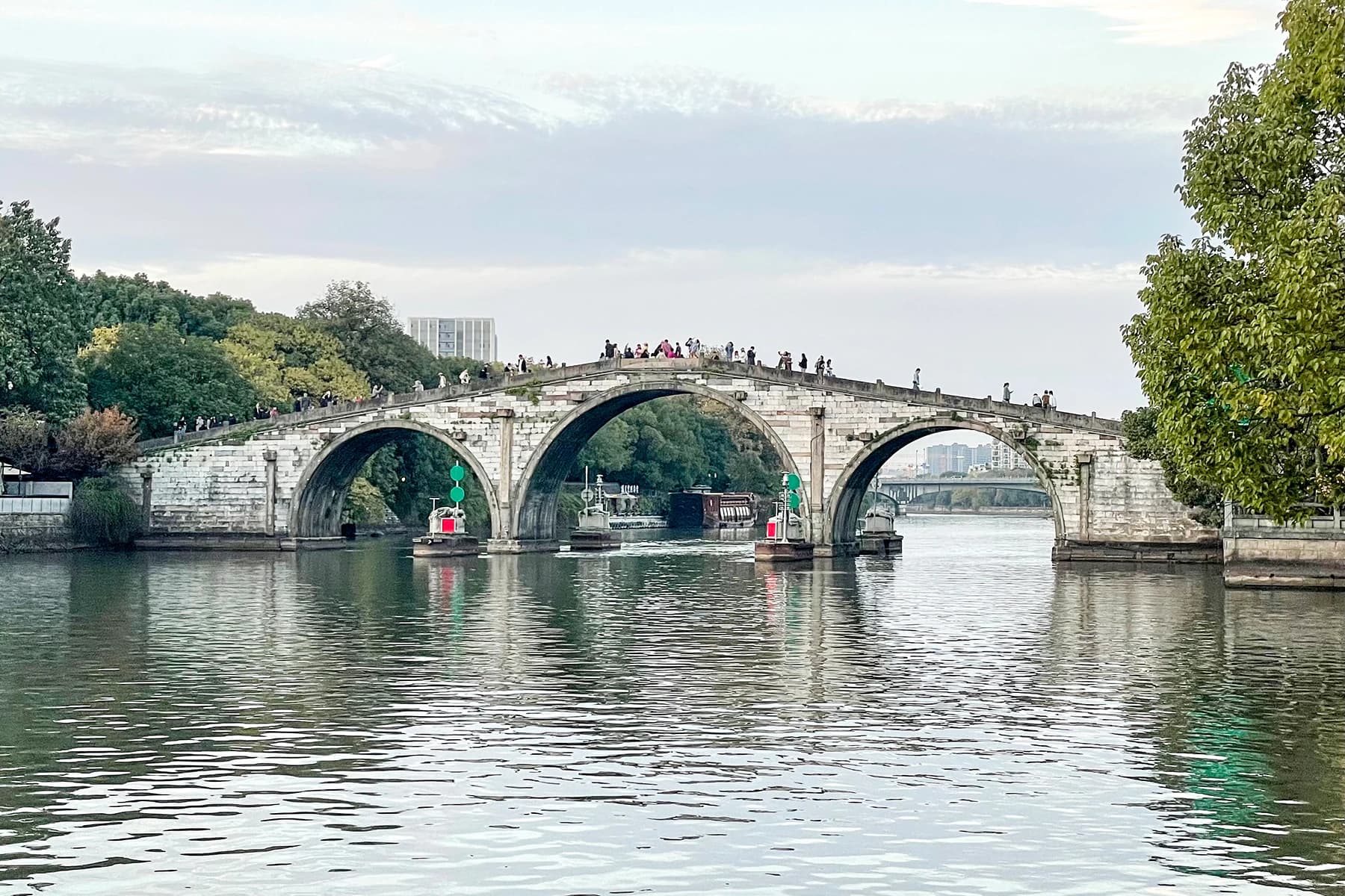 Gongchen Bridge visto al otro lado del canal, con sus arcos de piedra reflejados en el agua